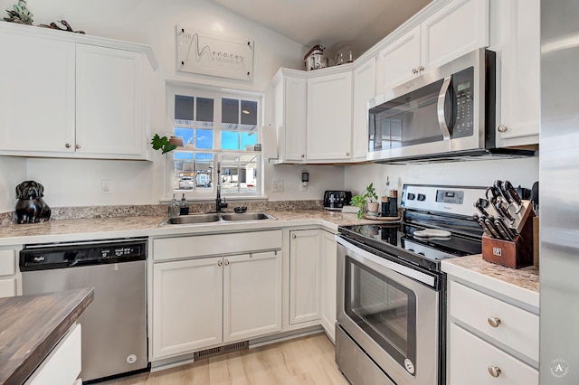 kitchen featuring stainless steel appliances, light countertops, visible vents, white cabinets, and a sink