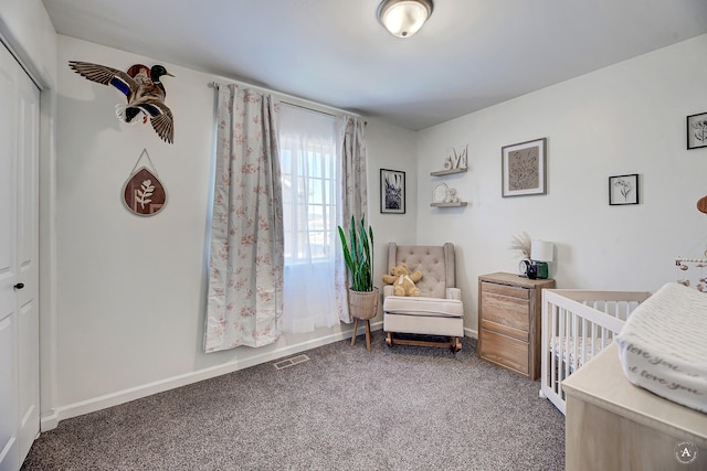 carpeted bedroom with a closet, visible vents, a crib, and baseboards