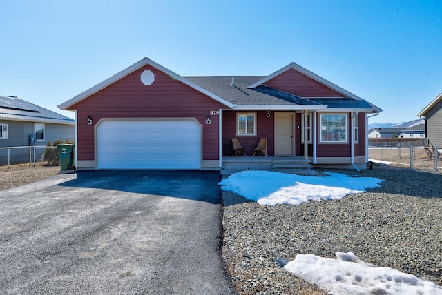 view of front of property featuring a shingled roof, fence, driveway, and a garage