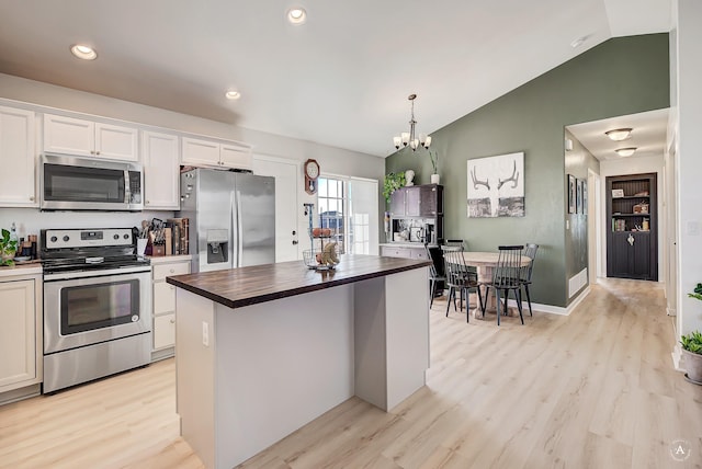 kitchen featuring appliances with stainless steel finishes, white cabinetry, vaulted ceiling, and light wood finished floors