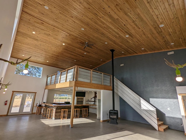 unfurnished living room with high vaulted ceiling, french doors, wooden ceiling, and a wood stove