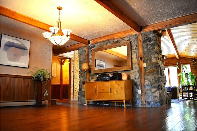 unfurnished dining area featuring a notable chandelier, wood-type flooring, baseboard heating, wainscoting, and beamed ceiling