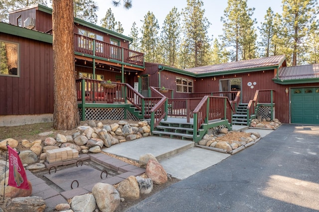 437 Tie Chute Ln, Florence, MT 59833 - view of front of property featuring a wooden deck, metal roof, driveway, and an attached garage