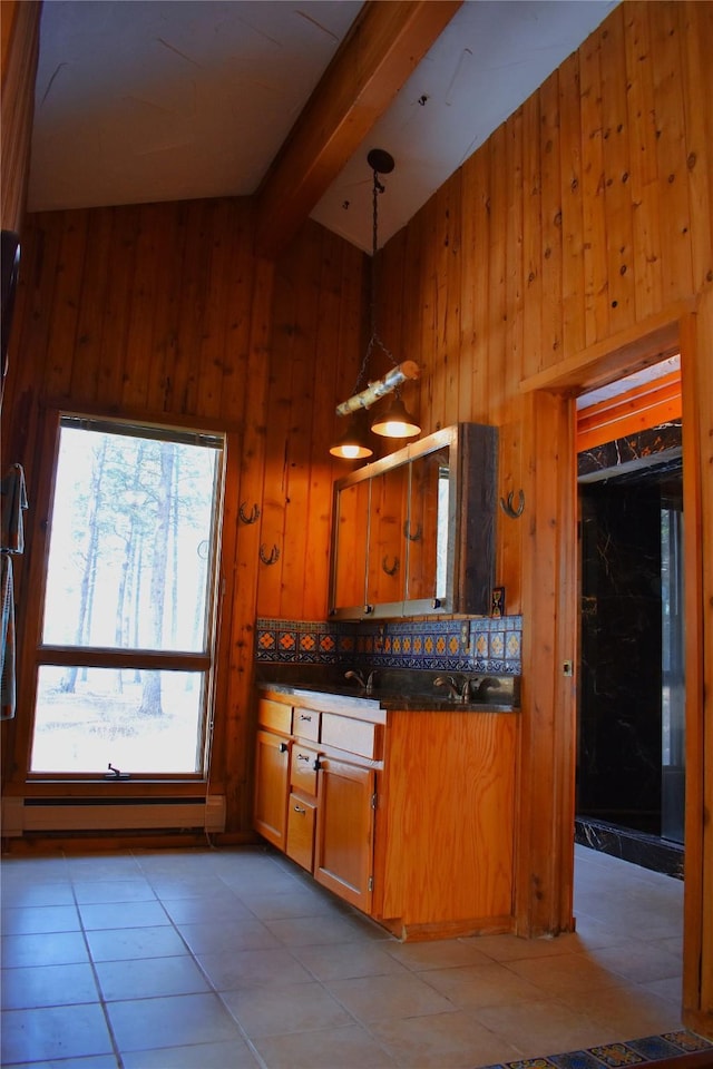 kitchen featuring dark countertops, wood walls, brown cabinetry, and beamed ceiling