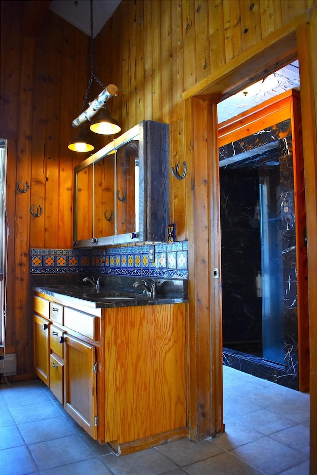 kitchen with wooden walls, decorative backsplash, brown cabinetry, dark countertops, and hanging light fixtures