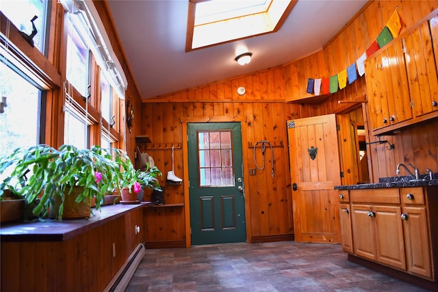 foyer featuring vaulted ceiling with skylight, wood walls, and baseboard heating