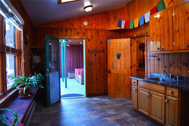 kitchen with lofted ceiling, wood walls, a sink, and brown cabinetry