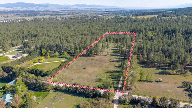 437 Tie Chute Ln, Florence, MT 59833 - aerial view of property and surrounding area with a forest, property boundaries highlighted, and mountains