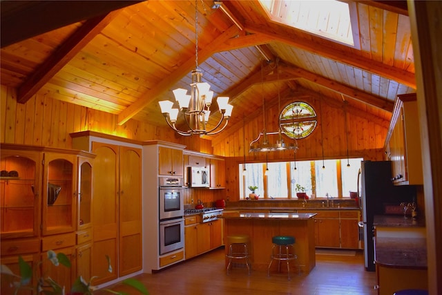 kitchen with lofted ceiling with beams, stainless steel appliances, a center island, and wooden walls