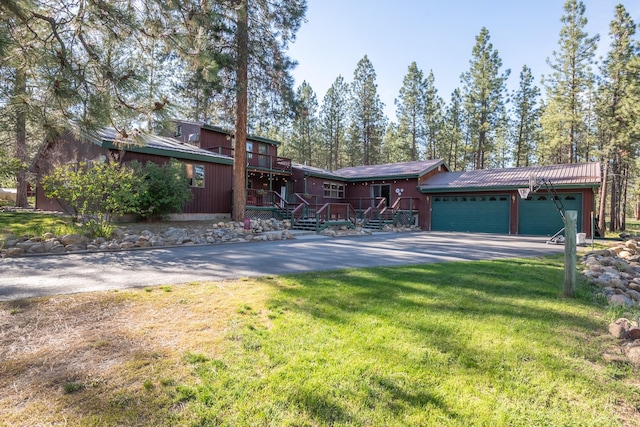 437 Tie Chute Ln, Florence, MT 59833 - view of front of house with driveway, a garage, a front lawn, and metal roof