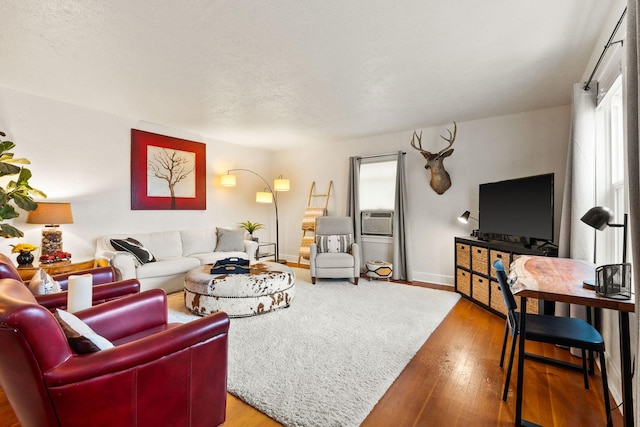 living room featuring cooling unit, baseboards, and hardwood / wood-style flooring