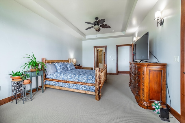 bedroom with a ceiling fan, baseboards, a raised ceiling, and carpet flooring