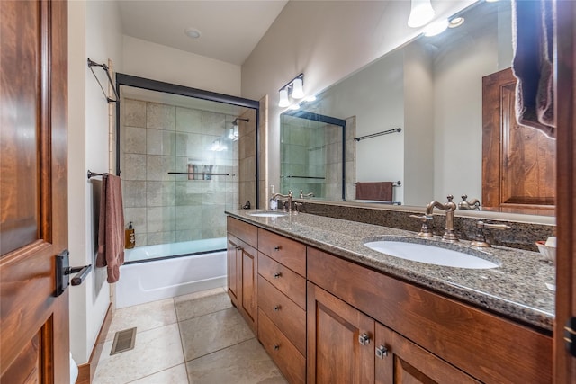 full bath with tile patterned flooring, visible vents, bath / shower combo with glass door, and a sink