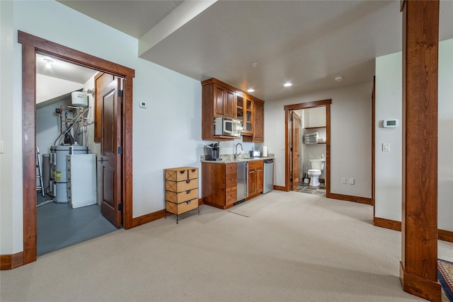 kitchen featuring stainless steel appliances, light colored carpet, water heater, brown cabinetry, and glass insert cabinets