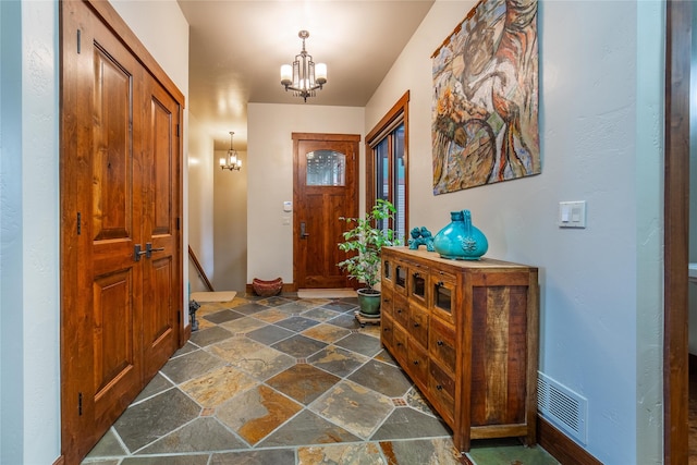 entryway with stone tile flooring, visible vents, and a notable chandelier