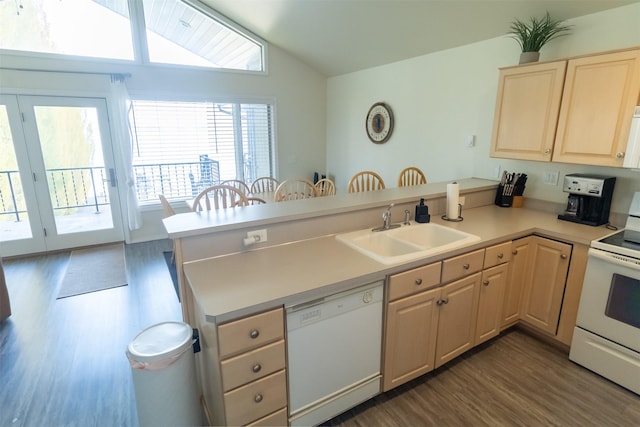 kitchen with a peninsula, white appliances, a sink, and light brown cabinetry