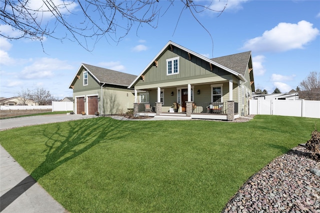 craftsman-style house featuring a front lawn, driveway, a porch, fence, and board and batten siding