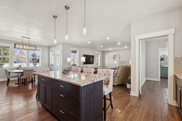 kitchen with baseboards, a breakfast bar area, and dark wood-style flooring