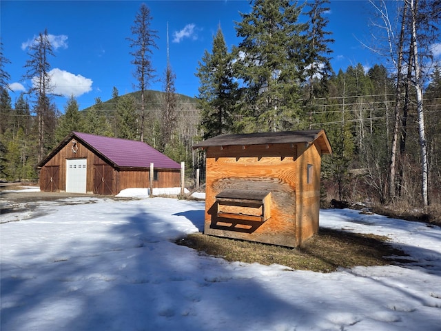 exterior space featuring an outbuilding, a detached garage, and a wooded view