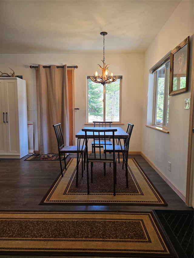 dining space featuring a chandelier, a wealth of natural light, dark wood-style flooring, and baseboards