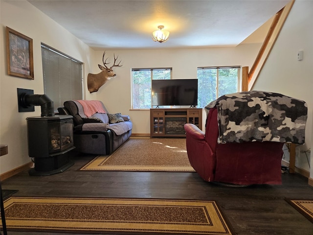 living room with wood finished floors, a wood stove, and baseboards