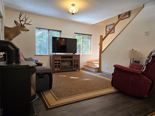 living area featuring a wood stove, baseboards, stairway, and wood finished floors