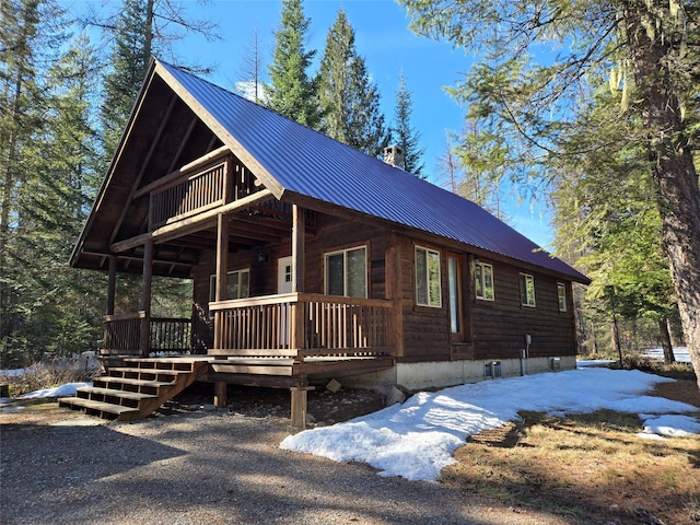 view of front facade featuring covered porch, metal roof, and a chimney