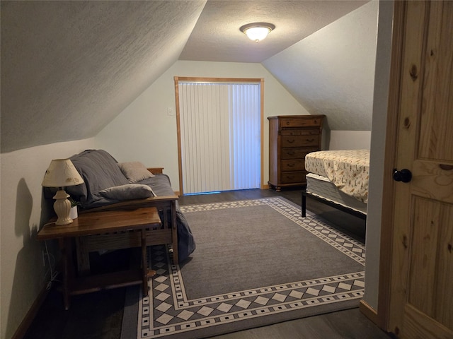 bedroom with a textured ceiling, wood finished floors, and lofted ceiling