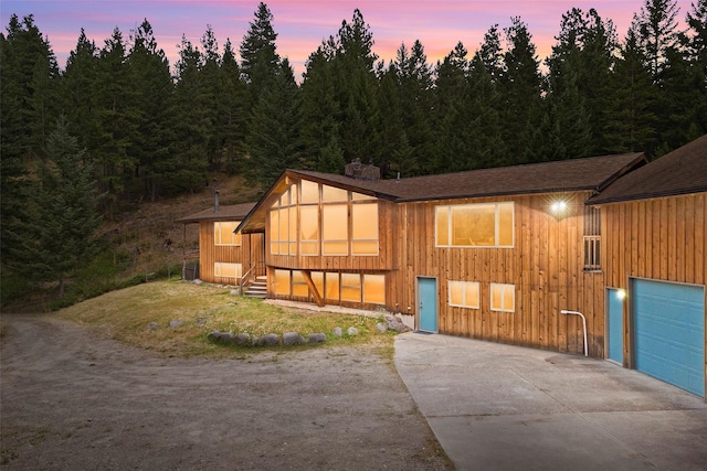 view of front of house featuring a garage, a front yard, concrete driveway, and a chimney