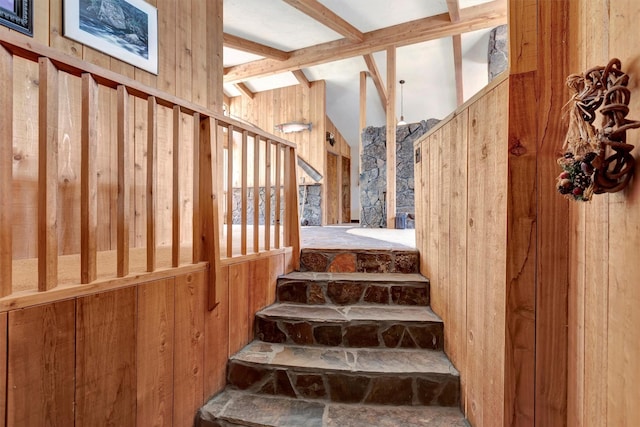 stairs featuring vaulted ceiling with beams and wood walls