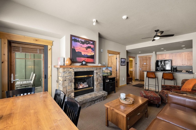 carpeted living area featuring a fireplace and a ceiling fan