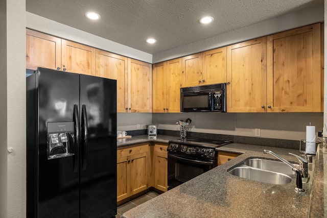 kitchen featuring recessed lighting, a sink, a textured ceiling, dark tile patterned flooring, and black appliances