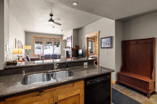 kitchen featuring black dishwasher, a textured wall, ceiling fan, open floor plan, and a sink