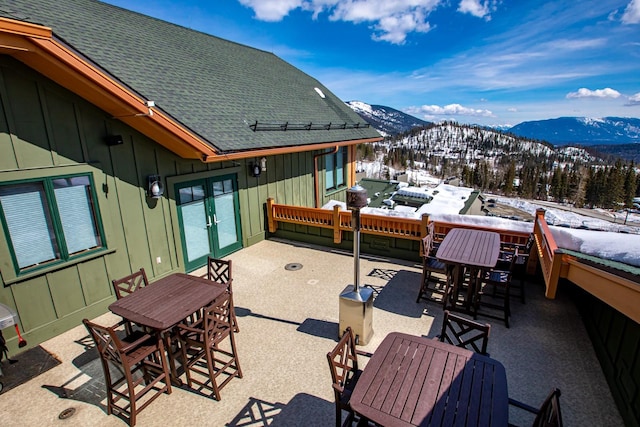 snow covered patio with outdoor dining area and a mountain view