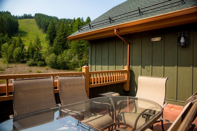 deck with outdoor dining space and a view of trees