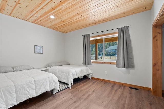 bedroom with wooden ceiling, baseboards, visible vents, and wood finished floors