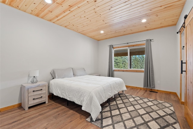 bedroom featuring wood ceiling, light wood finished floors, a barn door, and baseboards