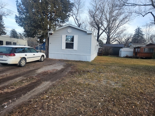 view of side of home with a lawn and dirt driveway