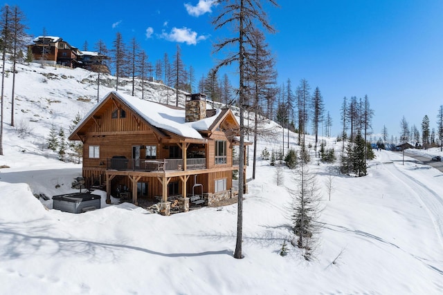 snow covered house with a garage and a chimney