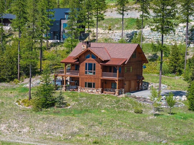 476 Elk Highlands Dr, Whitefish, MT 59937 - rear view of property featuring a balcony, driveway, an attached garage, and a chimney
