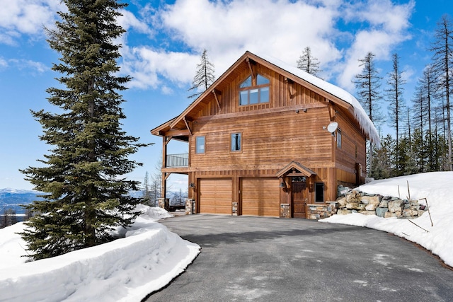 view of snow covered exterior with aphalt driveway and an attached garage