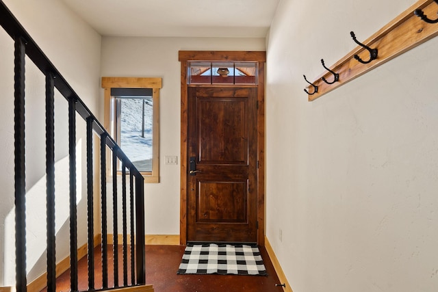 foyer with stairs, finished concrete floors, and baseboards