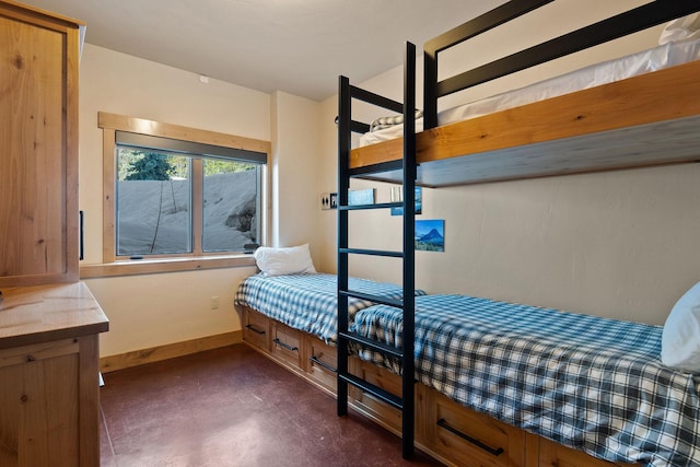 bedroom with finished concrete floors and baseboards