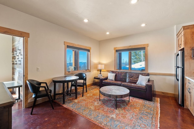 living area featuring baseboards, concrete flooring, and recessed lighting