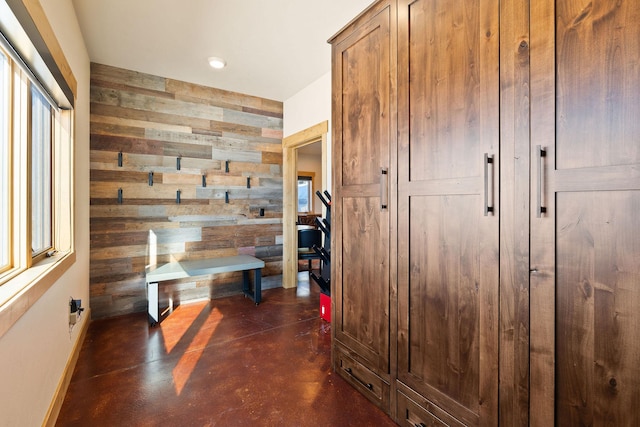 mudroom featuring baseboards, an accent wall, concrete flooring, wood walls, and recessed lighting