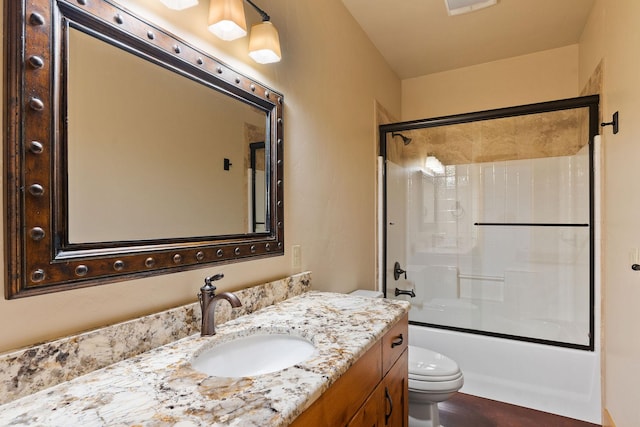 bathroom with toilet, bath / shower combo with glass door, and vanity