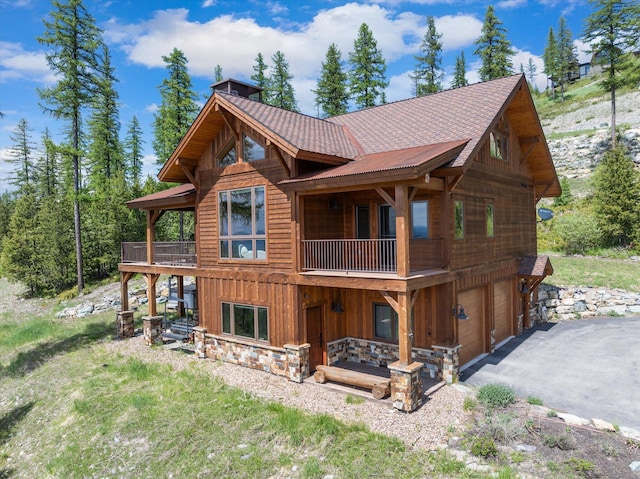 476 Elk Highlands Dr, Whitefish, MT 59937 - back of house featuring driveway, an attached garage, a chimney, and a balcony