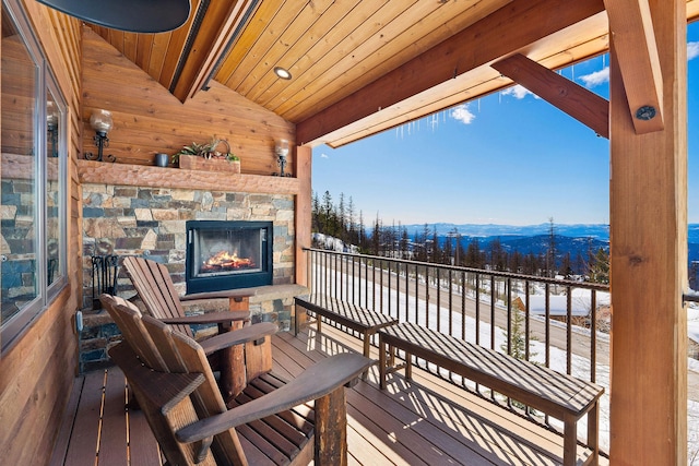 wooden deck with an outdoor stone fireplace and a mountain view