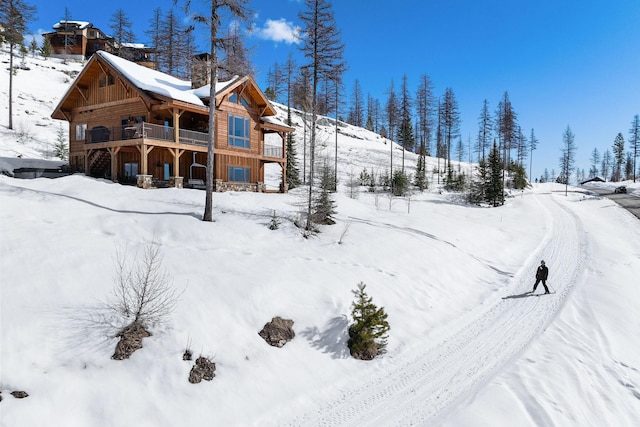 snow covered back of property featuring a garage and board and batten siding