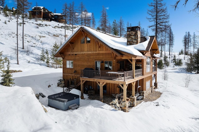 476 Elk Highlands Dr, Whitefish, MT 59937 - snow covered house with board and batten siding, a chimney, and a wooden deck
